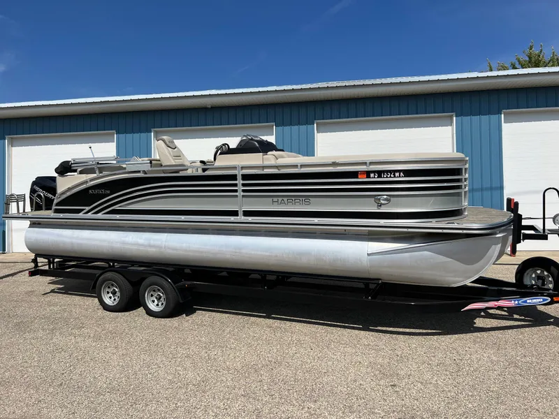 Slide: The Image of 2020 Harris FloteBote H SOL 250 CWDH TT pontoon boat on trailer, parked outdoors. - 2
