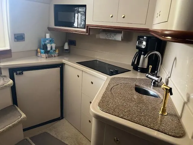 Slide: The Image of 2001 Cruisers Yachts 3470 Express kitchen with microwave, stovetop, sink, and coffee maker. - 16