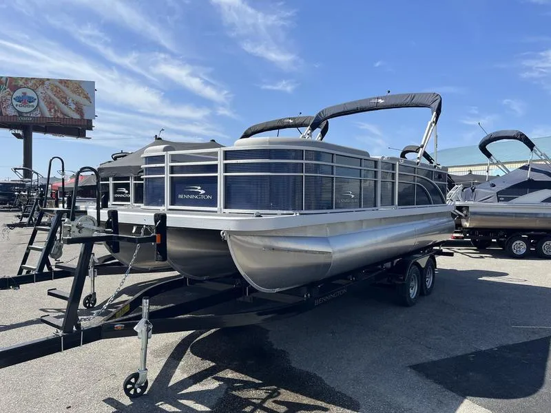 Slide: The Image of 2023 Bennington 22 SL pontoon boat on trailer under clear blue sky. - 2