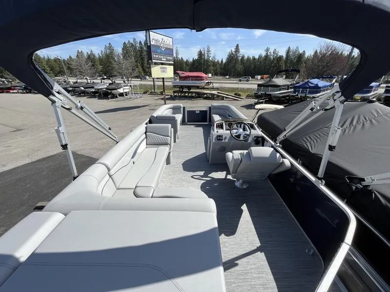 Slide: The Image of 2023 Bennington 22 SL pontoon boat interior with seating and helm, parked outdoors. - 5