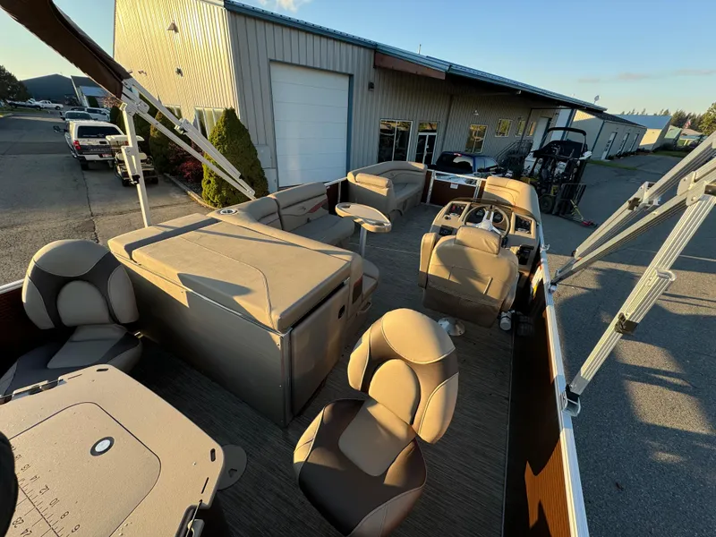 Slide: The Image of 2023 Bennington 22 SS pontoon boat interior with seating and helm, parked outside a warehouse. - 10