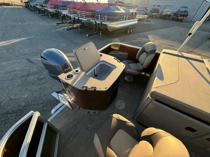 Slide: The Image of 2023 Bennington 22 SS pontoon boat interior with seating and motor, docked outdoors. - 11