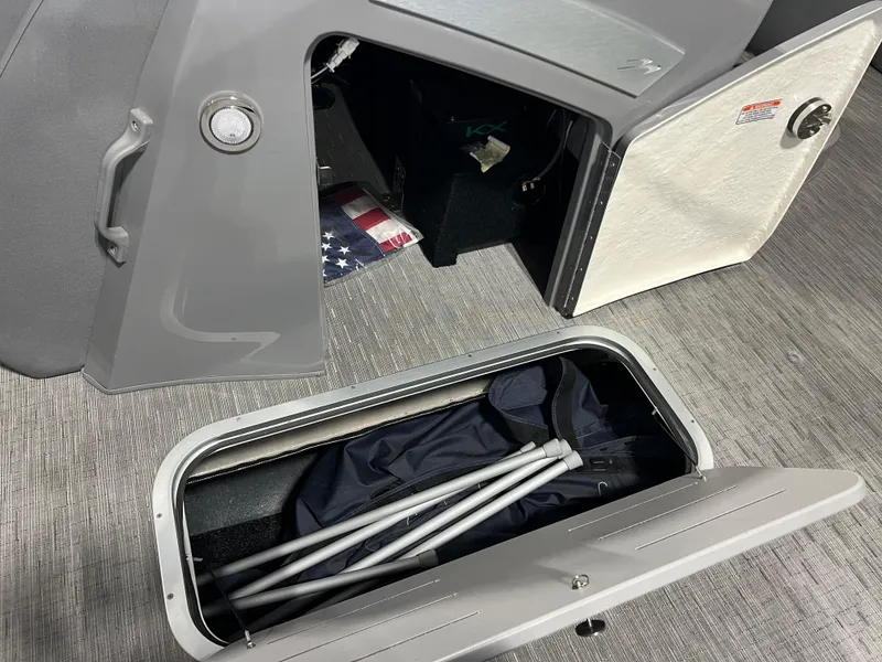 Slide: The Image of 2023 Bennington 23 LXFB boat storage compartments with American flag and folded equipment. - 12