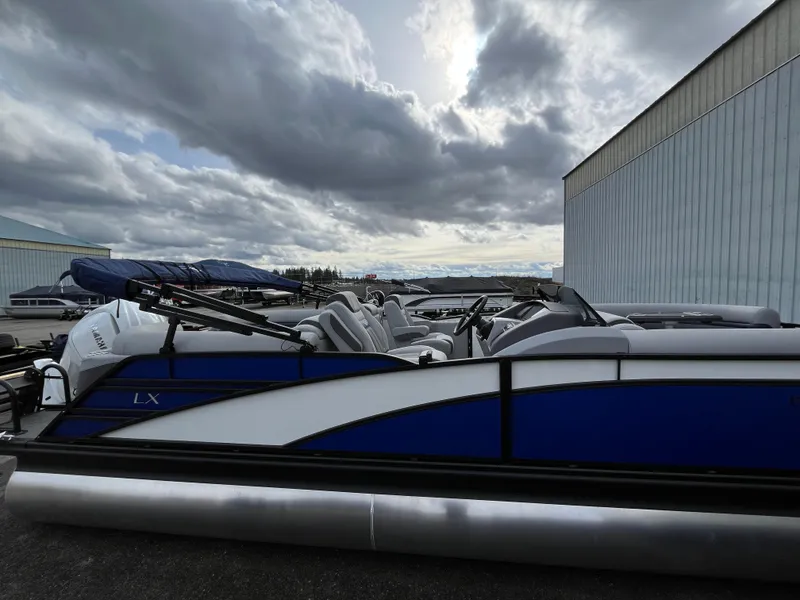 Slide: The Image of 2024 Bennington 24LXSFB pontoon boat under cloudy sky near warehouse. - 4