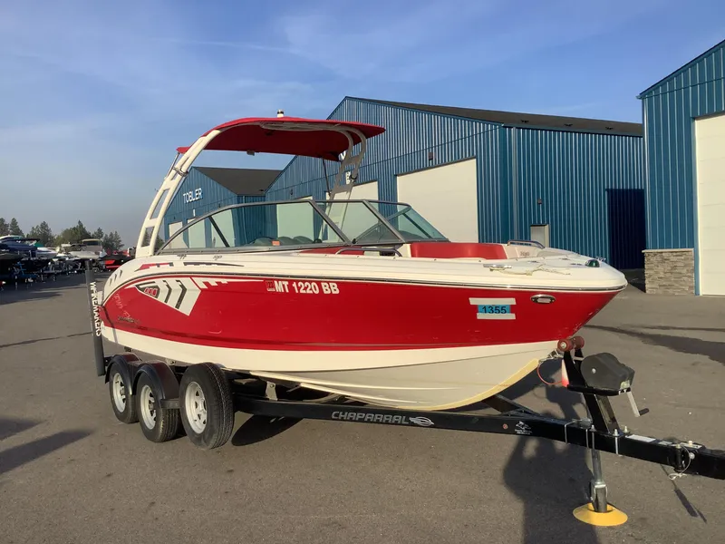 Slide: The Image of 2014 Chaparral 21 H2O boat on trailer, red and white, parked near blue buildings. - 6