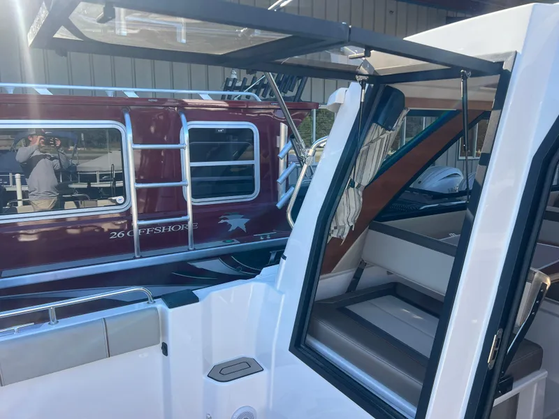 Slide: The Image of 2023 Cutwater C-248 C boat with open cabin door, docked beside a red vessel. - 12