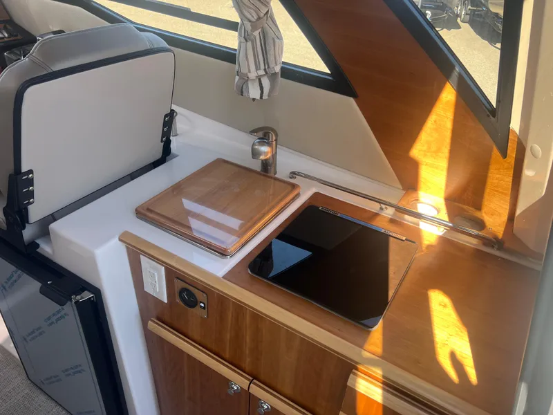 Slide: The Image of 2023 Cutwater C-248 C interior with kitchenette, featuring wooden surfaces and modern appliances. - 29