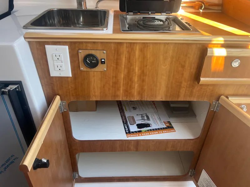 Slide: The Image of 2023 Cutwater C-248 C boat kitchen with sink, stove, and wooden cabinetry. - 31