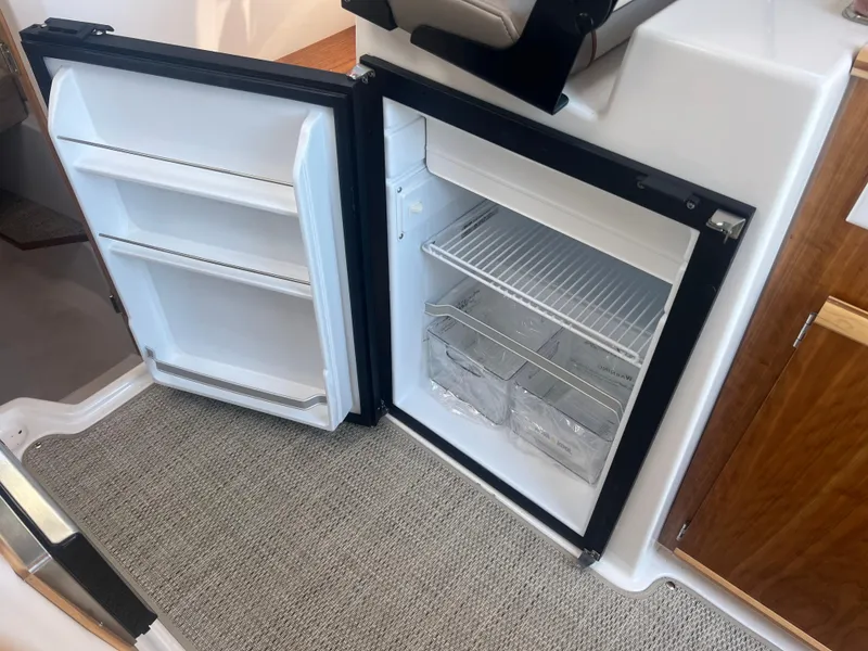Slide: The Image of 2023 Cutwater C-248 C boat interior with open refrigerator on carpeted floor. - 33