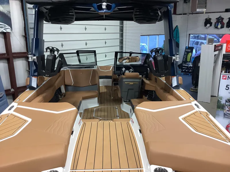 Slide: The Image of 2025 Nautique G23 boat interior with tan seating and sleek design in showroom. - 11