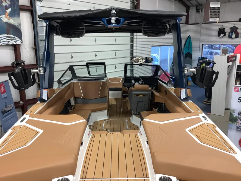 Slide: The Image of 2025 Nautique G23 boat interior with tan seating and advanced features in showroom. - 16