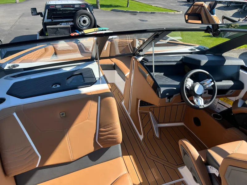 Slide: The Image of 2025 Nautique G23 boat interior with tan leather seats and sleek dashboard design. - 20