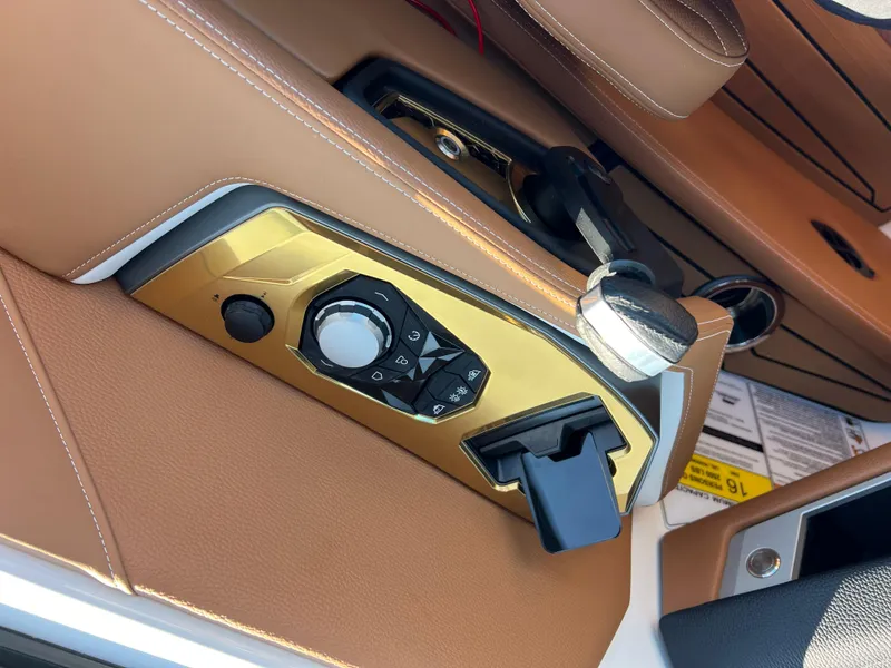 Slide: The Image of 2025 Nautique G23 boat interior control panel with tan leather accents. - 22