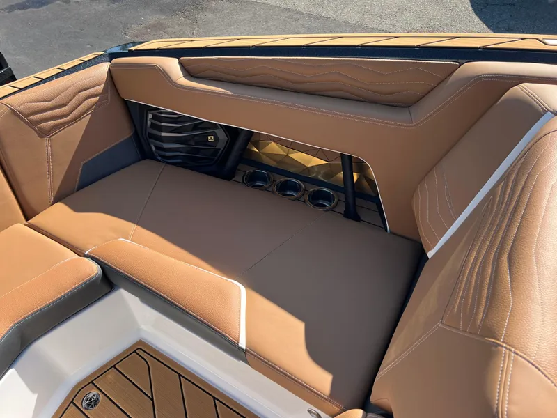 Slide: The Image of 2025 Nautique G23 boat interior with tan leather seating and cup holders. - 30