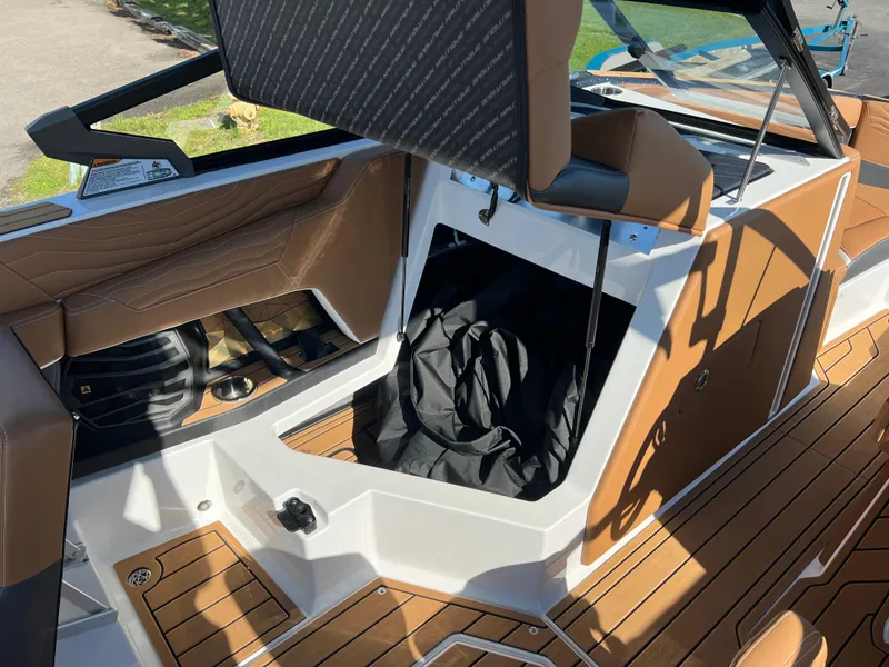 Slide: The Image of 2025 Nautique G23 boat interior with brown leather seats and storage compartment. - 33