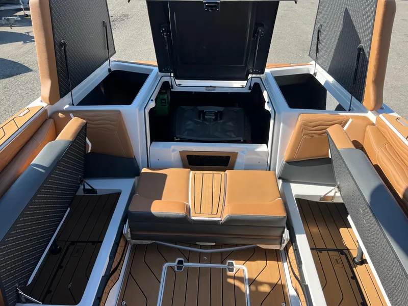 Slide: The Image of 2025 Nautique G23 boat interior with tan and black seating, open storage compartments. - 39