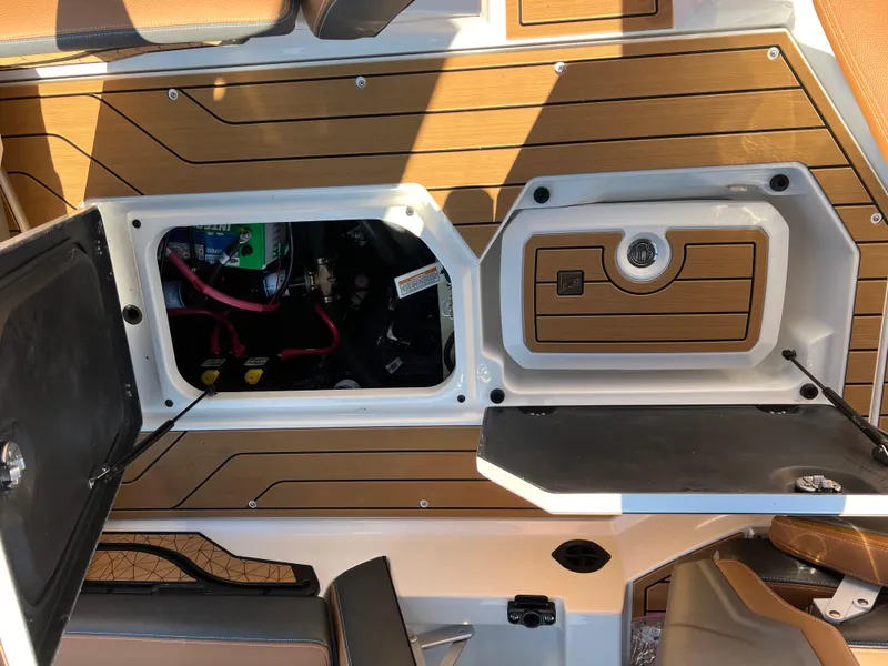 Slide: The Image of 2025 Nautique G23 boat storage compartment with open hatch and visible wiring. - 48