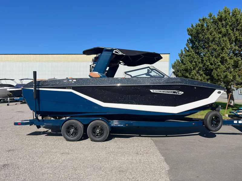 Slide: The Image of 2025 Nautique G23 boat on trailer, parked outdoors under clear blue sky. - 49