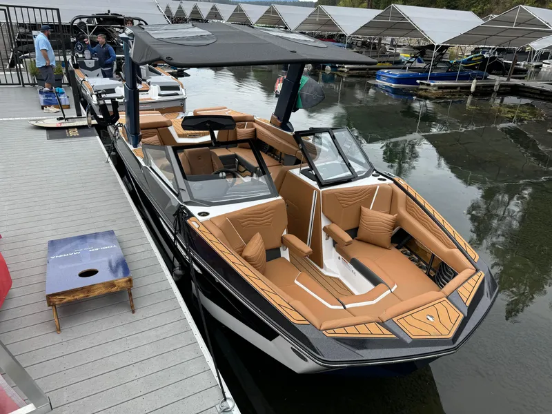 Slide: The Image of 2025 Nautique G23 boat docked, featuring luxurious tan seating and sleek design. - 7