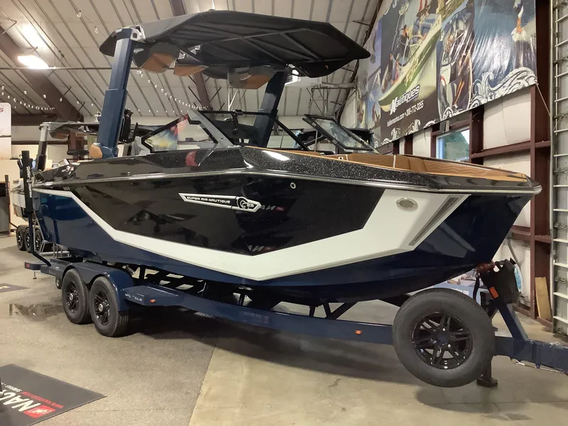 Slide: The Image of 2025 Nautique G23 boat on trailer in showroom, sleek design, black and white exterior. - 9