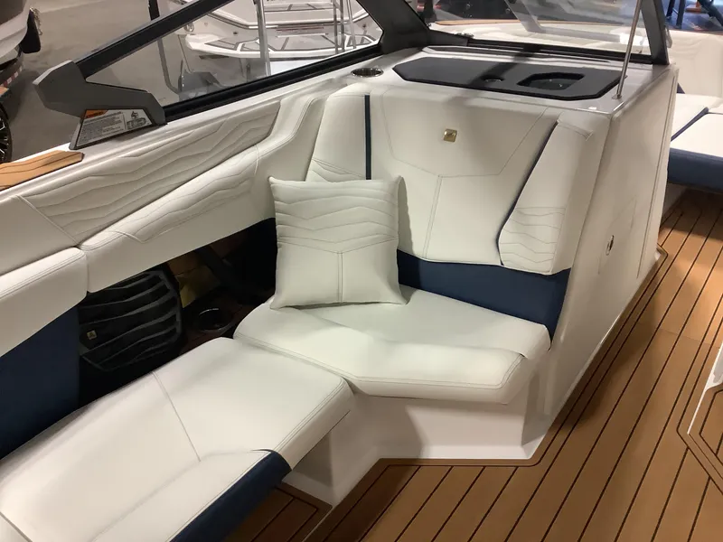 Slide: The Image of 2025 Nautique G25 boat interior with white and blue seating, wooden flooring. - 17