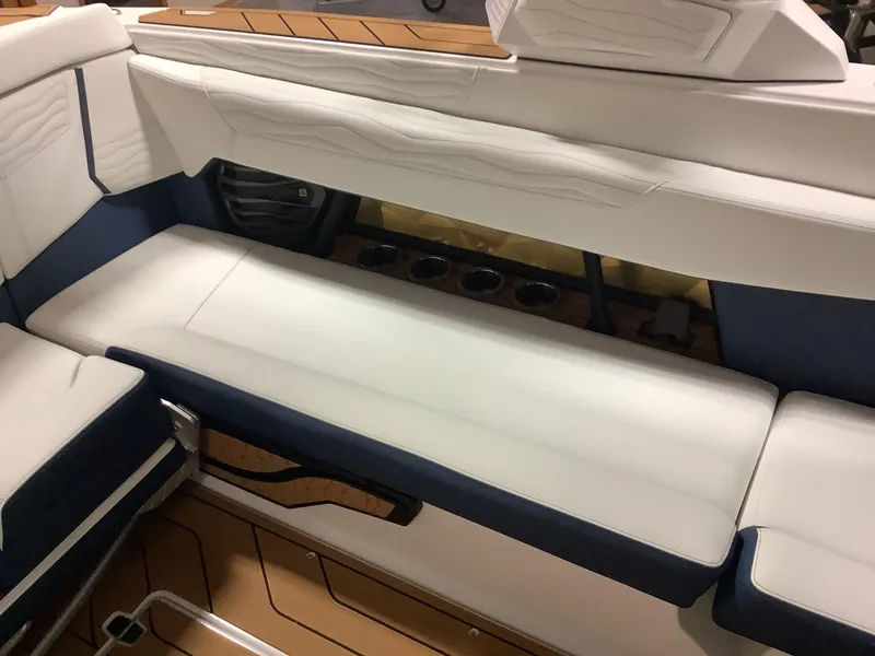 Slide: The Image of 2025 Nautique G25 boat interior with white and navy seating, cup holders, and wood accents. - 18