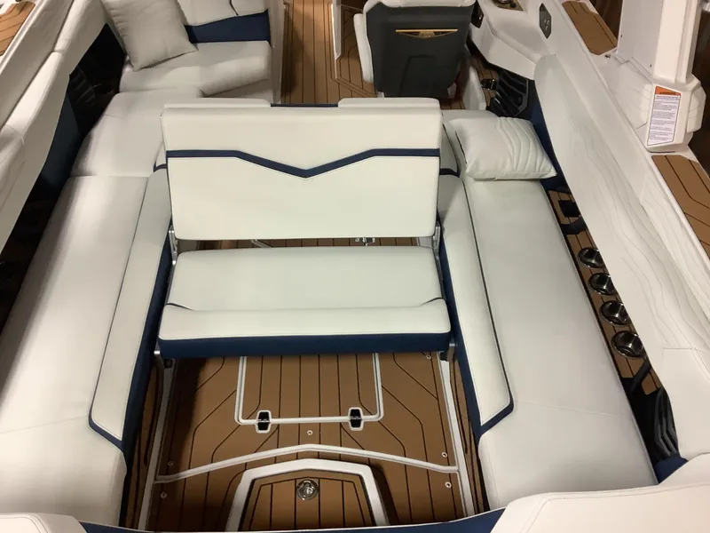 Slide: The Image of 2025 Nautique G25 boat interior with white and navy seating, teak flooring, and cup holders. - 22