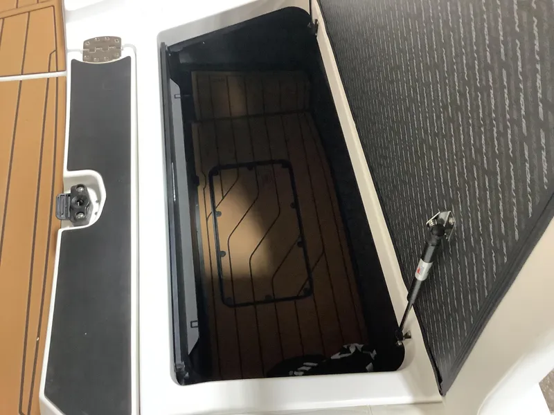 Slide: The Image of 2025 Nautique G25 storage compartment with open lid and hydraulic support. - 24