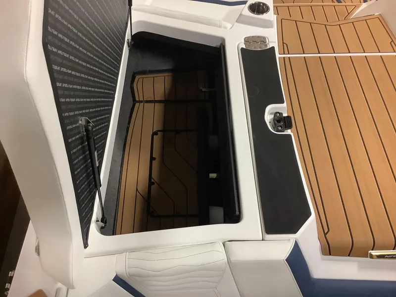 Slide: The Image of 2025 Nautique G25 boat storage compartment with teak flooring and white upholstery. - 25