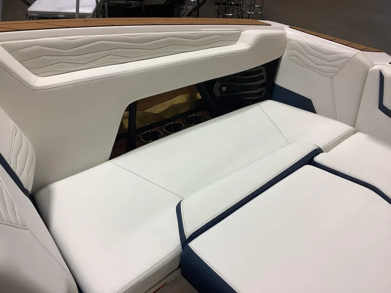 Slide: The Image of 2025 Nautique G25 boat interior with white and blue seating, featuring modern design and cup holders. - 9