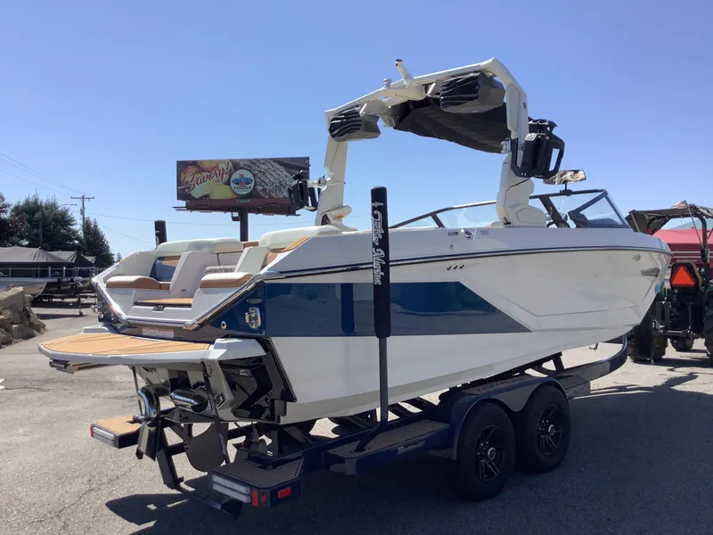 Slide: The Image of 2024 Nautique Super Air G23 boat on trailer, blue and white design, sunny day. - 10