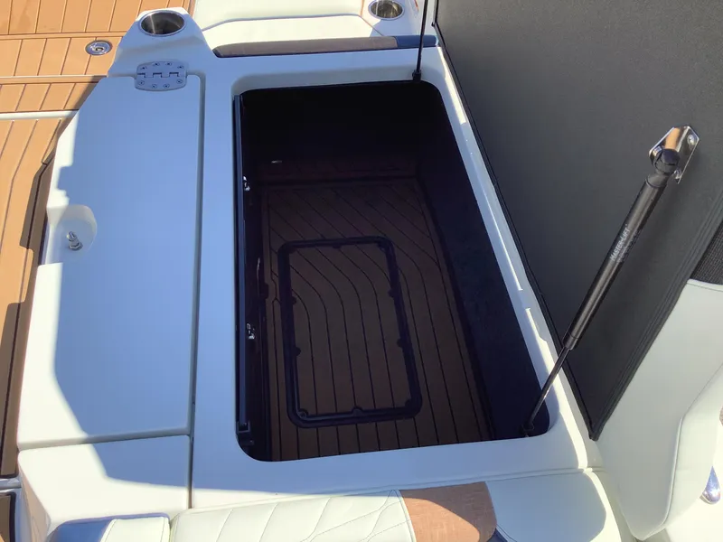 Slide: The Image of 2024 Nautique Super Air G23 storage compartment with open hatch and teak flooring. - 24