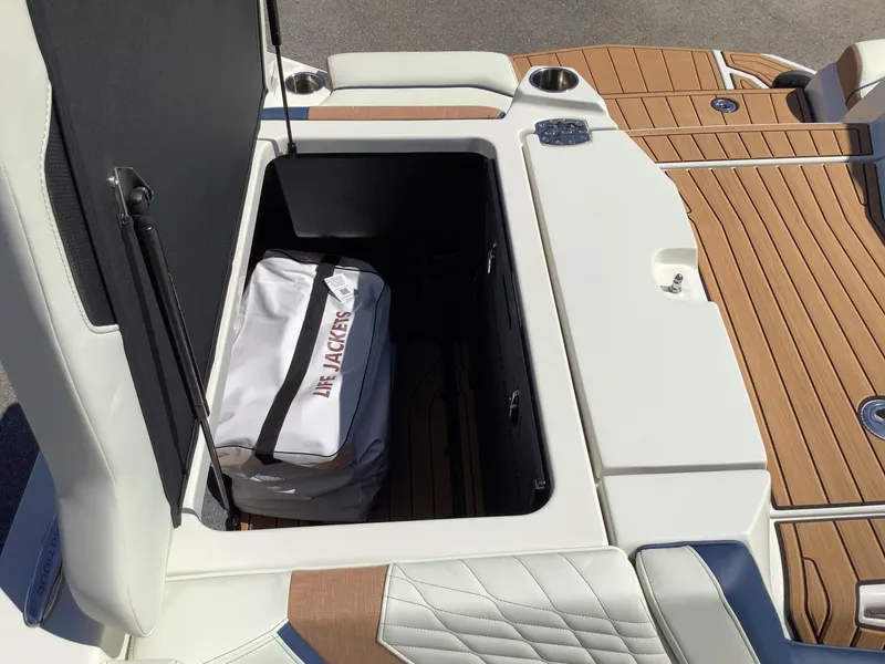 Slide: The Image of 2024 Nautique Super Air G23 storage compartment with life jackets on teak deck. - 25