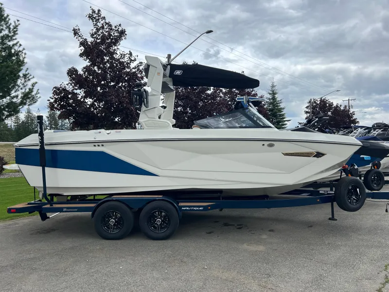 Slide: The Image of 2024 Nautique Super Air G23 boat on trailer, white and blue design, parked outdoors. - 8