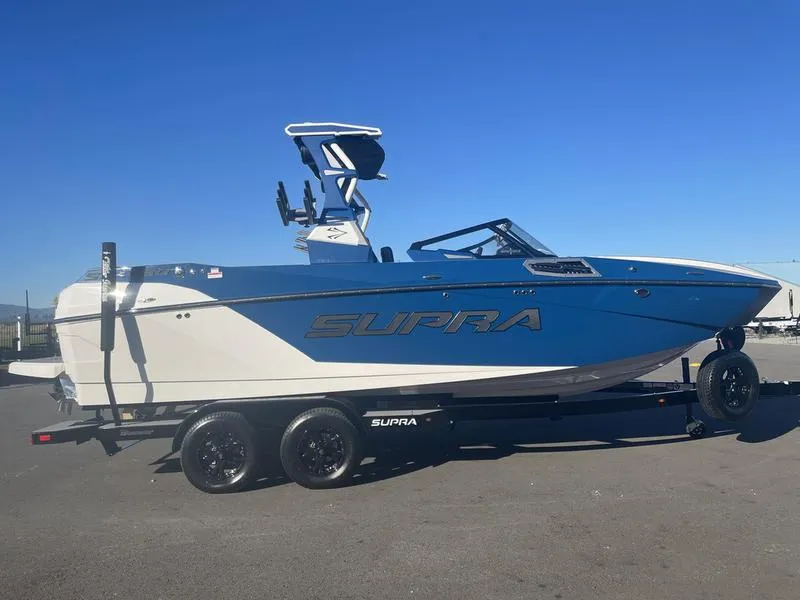 Slide: The Image of 2023 Supra SA 450 boat on trailer, blue and white design, clear sky background. - 5