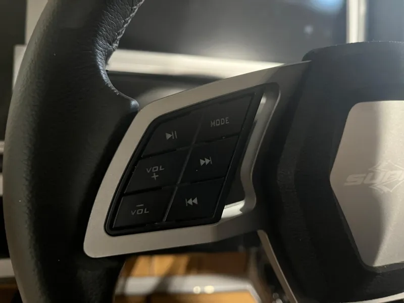 Slide: The Image of Close-up of 2023 Supra SE 550 steering wheel controls, featuring volume and mode buttons. - 23