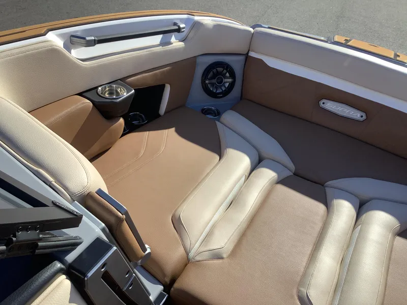 Slide: The Image of 2023 Supra SE 550 boat interior with tan and cream seating, cup holders, and speaker. - 42