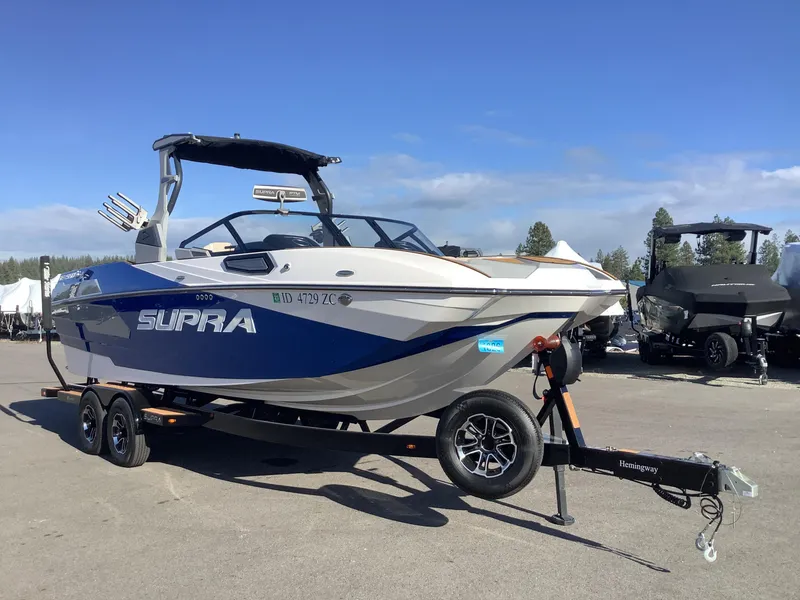 Slide: The Image of 2023 Supra SE 550 boat on trailer, parked outdoors under clear blue sky. - 5