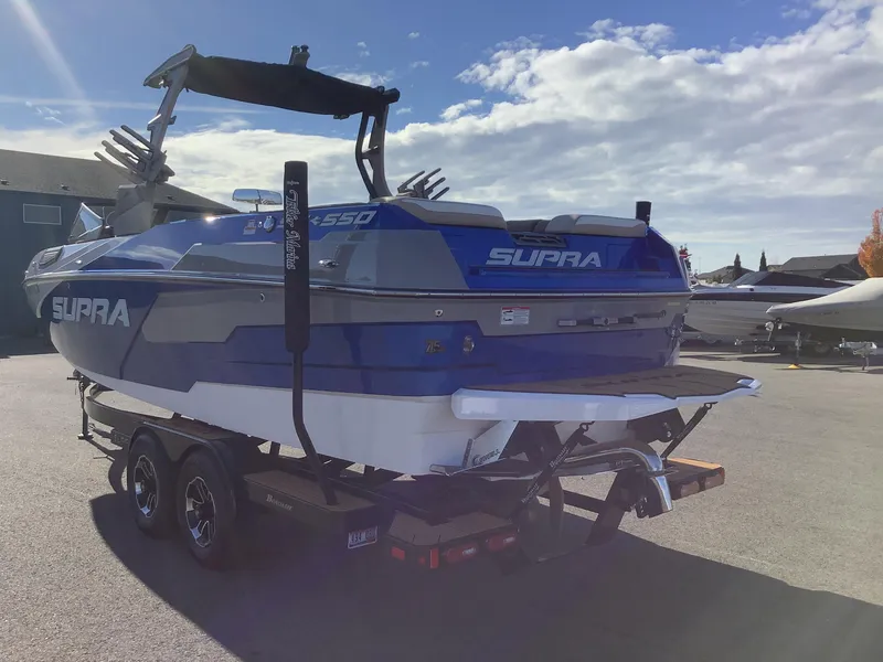 Slide: The Image of 2023 Supra SE 550 boat on trailer, blue and white design, sunny day. - 9