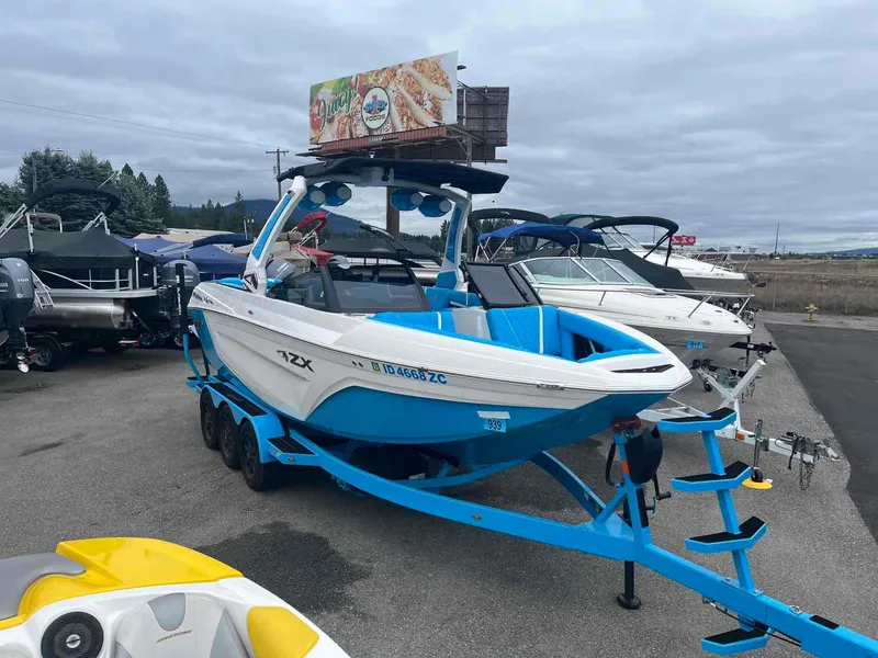 Slide: The Image of 2023 Tigé 25ZX boat on trailer in a marina parking lot. - 3
