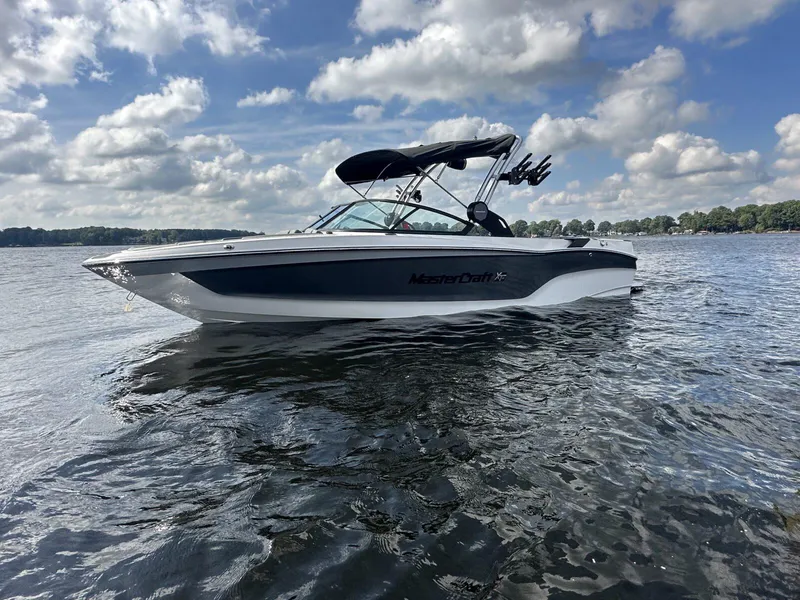 The Image of 2024 MasterCraft XT25 boat on a lake under a cloudy sky. - 0