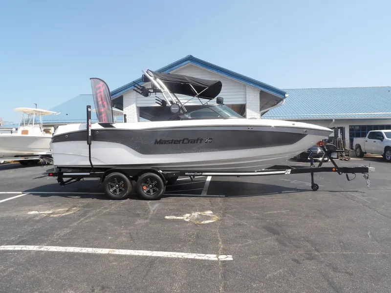 Slide: The Image of 2024 MasterCraft XT25 boat on trailer in parking lot. - 2