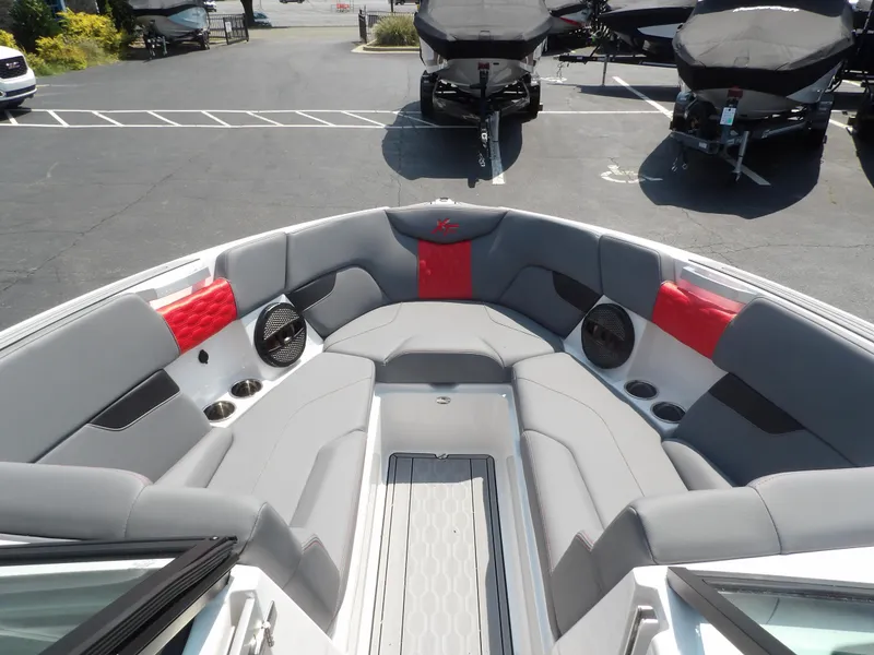 Slide: The Image of 2024 MasterCraft XT25 boat interior with gray and red seating, cup holders, and speakers. - 9