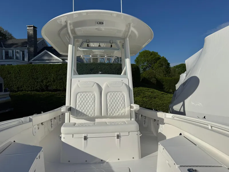 Slide: The Image of 2025 Regulator 26XO boat with white seating and console, docked near a house. - 18