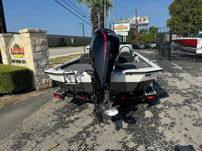 Slide: The Image of 2025 Vexus AVX 1880 boat with outboard motor, parked outdoors. - 2