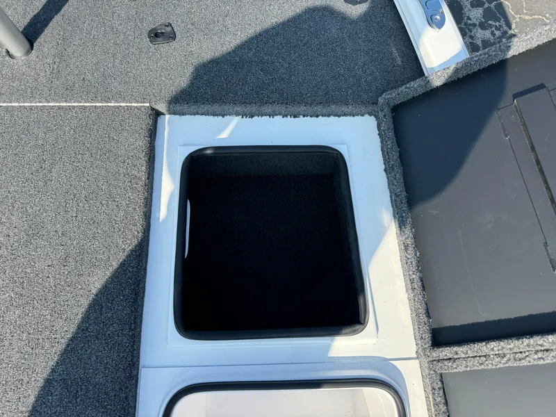Slide: The Image of 2025 Vexus AVX 1880 boat storage compartment with open hatch, gray carpeted interior. - 27