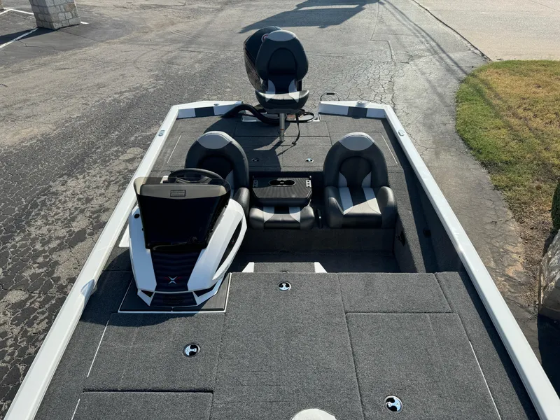 Slide: The Image of 2025 Vexus AVX 1880 boat interior with seating and console, parked on pavement. - 33