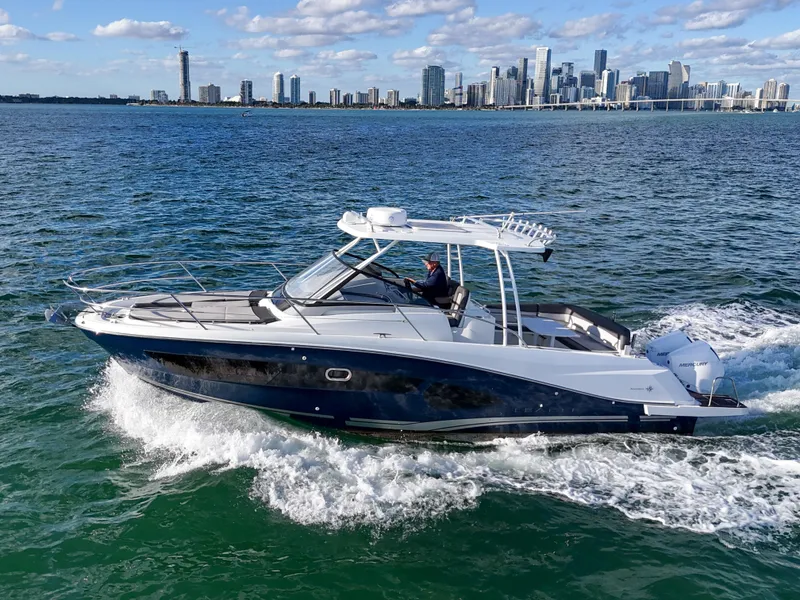 Slide: The Image of 2019 Jeanneau 34 boat cruising on water with city skyline in background. - 16