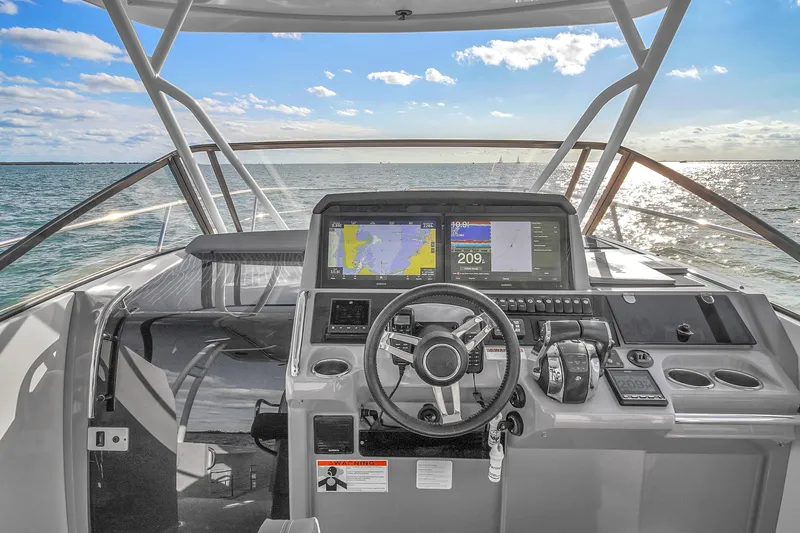 Slide: The Image of 2019 Jeanneau 34 boat cockpit with navigation screens, steering wheel, and ocean view. - 26