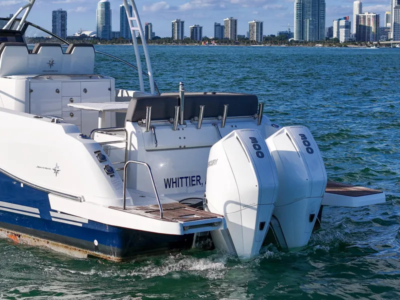 Slide: The Image of 2019 Jeanneau 34 boat with twin outboard motors on water, city skyline in background. - 9